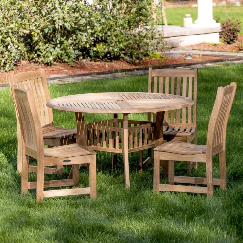 70040 Veranda Hyatt 5 piece teak Dining Set of 4 side chairs and 48 inch round dining table on grass lawn with concrete walkway and mulched landscaped area in background 