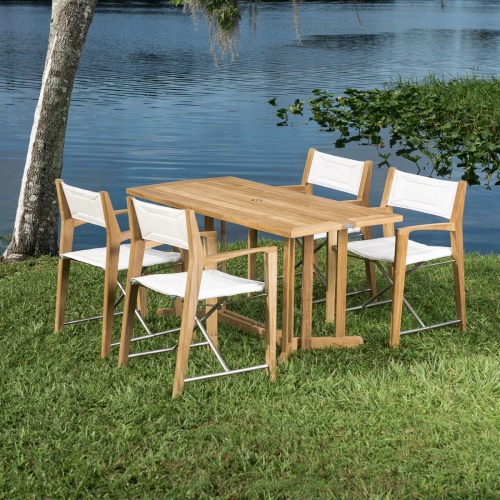 70476 Odyssey 5 piece Outdoor Dining Set of 4 folding director chairs and 5 foot rectangular teak dining table on grass field overlooking a blue lake