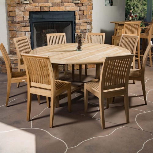 70493 buckingham laguna nine piece teak dining set vase of pinecones on stone patio with stone fireplace teak bar set with wine bottle and two glasses in background