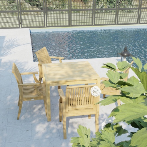 70555 Laguna 5 pc Square Dining Set of Bistro 36 inch Square Teak Dining Table and 4 Laguna Dining Armchairs in angled view on pool deck with pool and fence in the background 