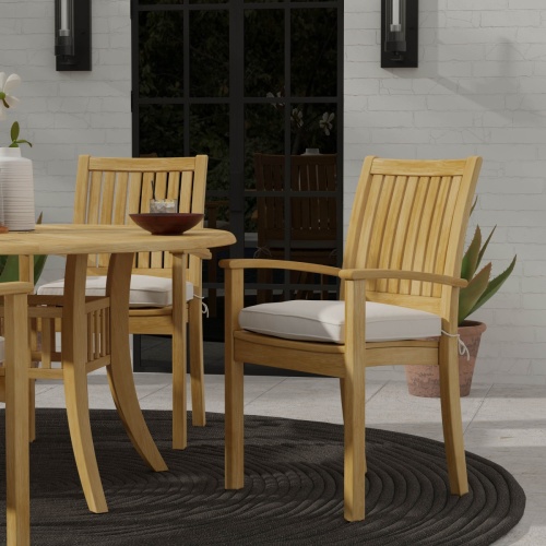 12196 Sussex teak stacking armchair with optional seat cushion angled on outdoor patio with french door and 2 candle scones and potted plant in background 