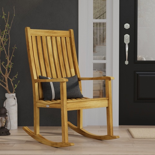 12223 veranda teak rocking chair  with throw pillow on seat on porch next to front door with lantern and plant in white container on right side in angle view with house in background