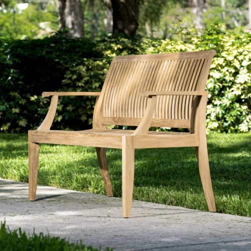 13810 Laguna 4 foot Teak Bench side angled on walkway with grass and trees in background