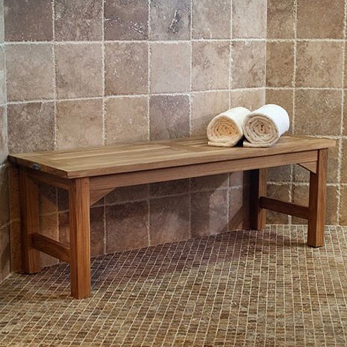 13940 Veranda 4 foot Teak Backless Bench angled view against a tiled wall shower area with 2 rolled white towels on top of bench