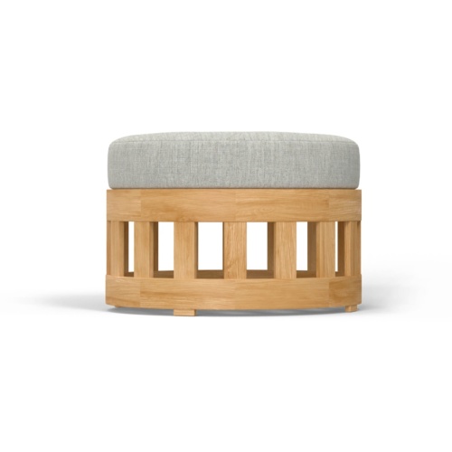 18170 Kafelonia teak coffee table ottoman with Natte Chine colored cushion on concrete patio in front of tall sea grass with the ocean in the background 