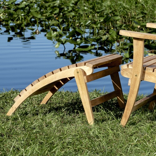 18607 adirondack teak footrest ottoman back angled view on grassy bank with water plants and water view