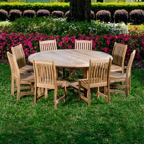 70020 Buckingham Veranda 9 piece teak Dining Set of 8 teak side chairs and  72 inch round table on grass with flowering shrubs and landscaped background