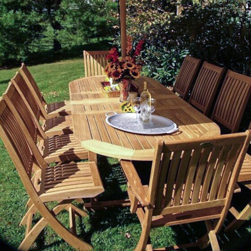 70050 Montserrat Barbuda 11 piece oval teak dining set fresh flowers pillar candle silver tray with wine bottle and glasses outside on green lawn   