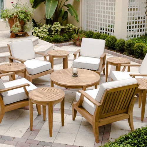 70106 laguna eleven piece lounge set on stone patio and stairs with potted plant pillar candle holder on coffee table surrounded by landscape shrubs and two lattice panels in background