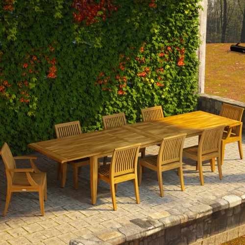 70123 Laguna 9 pc Teak Dining Set of Laguna 11 ft long Rectangle Dining Table and 2 Dining Armchairs and 6 Side Chairs on stone patio with flowering vines covering a wall in the background