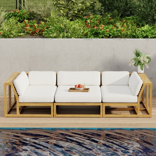 70274 Maya 3pc Daybed on patio in aerial front view with tray of fruit on middle daybed section facing a pool next to a potted plant with privacy wall with shrubs and trees in background