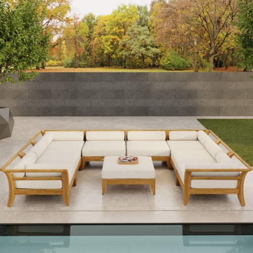 70282 Aman Dais 9 pc teak Daybed Sectional Set with bolsters and cushions angled on tiled patio with privacy wall and trees in background 