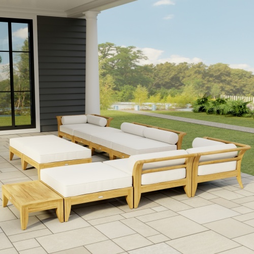 70285 Aman Dais 11 pc L Lounge Set in side angled view on covered tiled patio of house with landscape plants and fence in the background