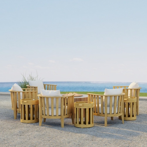 70421 Kafelonia 9 pc Fire Pit Seating Set showing 5 Kafelonia Club Chairs and 4 Side Chairs and Agora Fire Table in side view on outdoor patio with grass and ocean in the background  