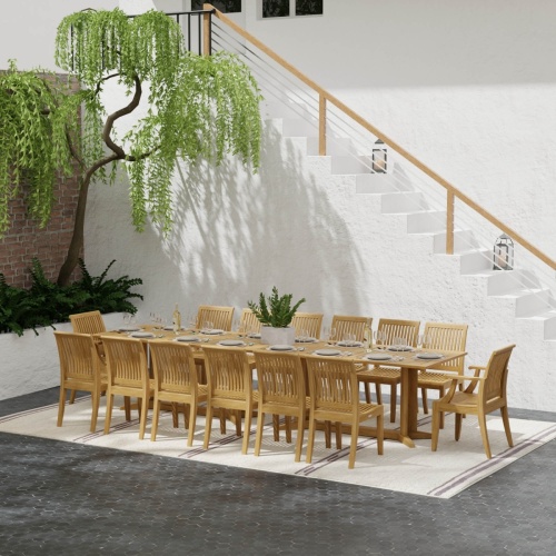 70436 Grand Pyramid 15 piece teak Dining Set with 14 place settings and wine bottles on outdoor terrace patio next to landscape planter and in front of staircase to house