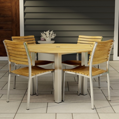70438 Vogue Dining Set for 4 of Vogue Teak and Stainless Steel 48 inch Round Dining Table and 4 Vogue Stacking Dining Chair angled top on patio with a door of house in the background 