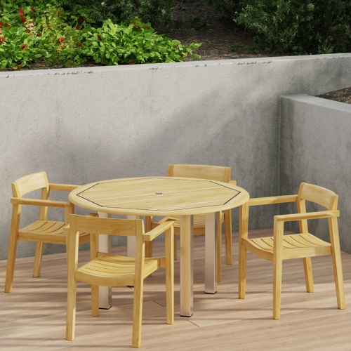 70478 Vogue Horizon Dining Set of 4 Horizon Dining Armchairs and Vogue 48 inch Round Teak and Stainless Steel Dining Table in angled aerial view on patio with privacy wall in back