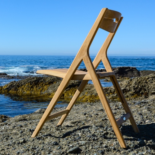 70589 Vogue Surf teak folding side chair on sandy beach facing ocean and blue sky
