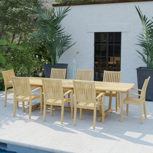 70759 Sussex Veranda 9 pc Teak Patio Dining Set in angled side view on pool deck behind a pool with house and windows and 2 potted plants in background 