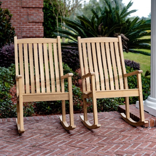 70777 veranda teak rocker chat set next to white pillar on red brick porch with shrubs grass and brick wall in background