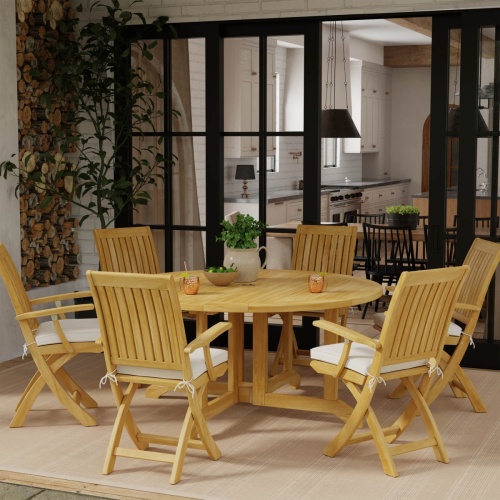 70850 Barbuda Folding Teak 7 pc Dining Set with optional seat cushions with copper mugs and flower vase pitcher on table on stone patio with french doors leading to kitchen in in background 