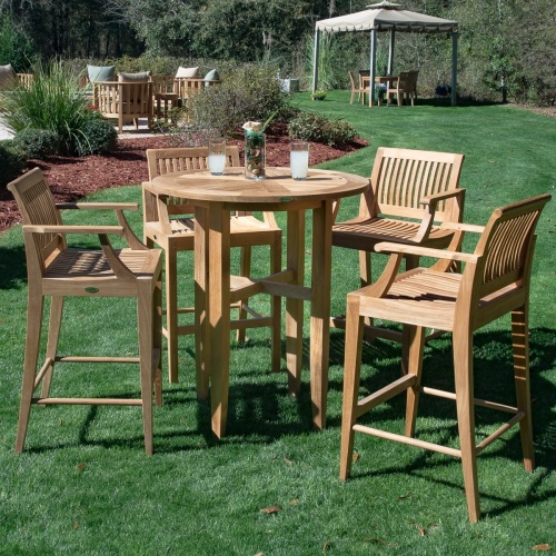 15817 Laguna 5 piece Teak Bar Table Set on grass field showing glass centerpiece and two drink glasses on table with shrubs and other furniture in background