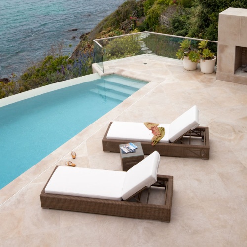 30002dp Malaga two cushioned synthetic wicker chaise loungers sandals between chaises on patio two magazines on side table angled towards pool fireplace glass rail ocean in background