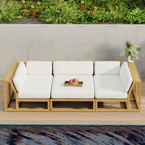 70274 Maya 3pc Daybed on patio in aerial front view with tray of fruit on middle daybed section facing a pool next to a potted plant with privacy wall with shrubs and trees in background