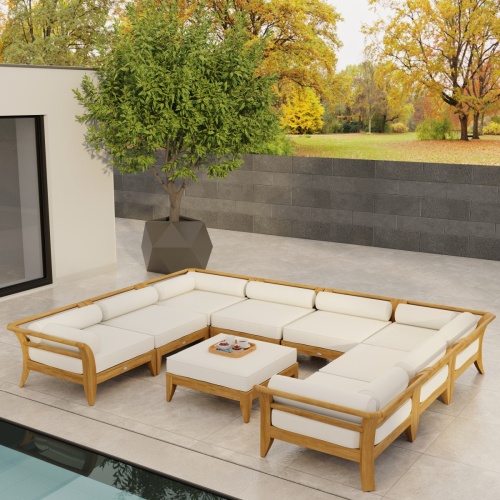 70282 Aman Dais 9 pc teak Daybed Sectional Set with bolsters and cushions angled aerial view on tiled patio with glass door and privacy wall and trees in background 