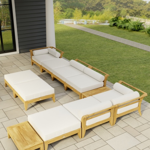 70285 Aman Dais 11 pc L Lounge Set in angled aerial view on covered tiled patio of house with landscape plants and fence in the background