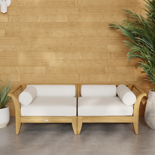 70429 Aman Dais Teak 2 pc Loveseat Set of 2 Aman Dais Corner Sectionals with cushions in angled front view on patio next to 2 potted plants against a wall in background