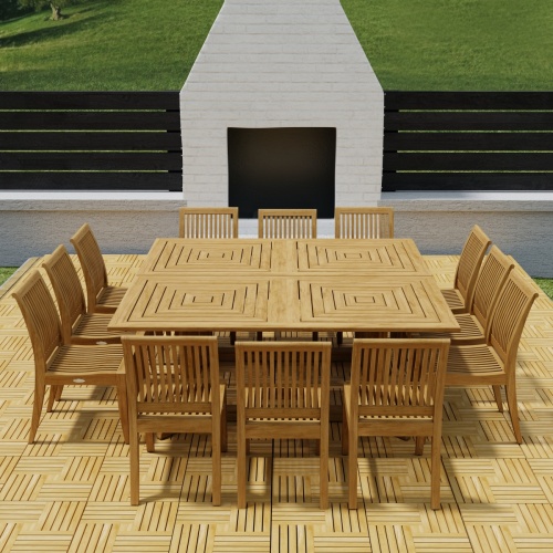 70435  Pyramid 14 pc Teak Dining Set on Teak Parquet floor deck angled top view in front of an outdoor fireplace with privacy wall and green lawn in background