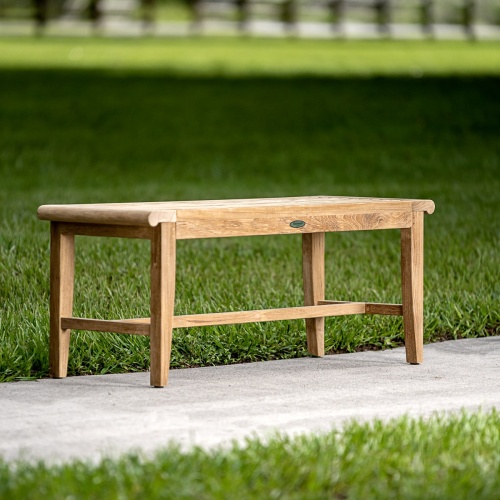 13915 Laguna 4 foot long teak Backless Bench on concrete walkway with grass in background