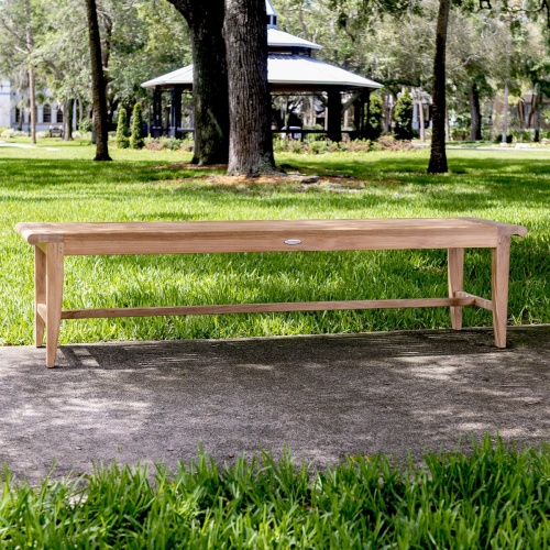 13917 Laguna 6 foot teak Backless Bench on concrete walkway with trees and pavilion in background
