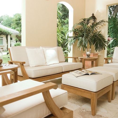 70105 Laguna 7 pc 66 inch Sofa Set on patio with pillar candle and glass holder on side table open magazine on ottoman potted palm tree in corner landscape and house in background