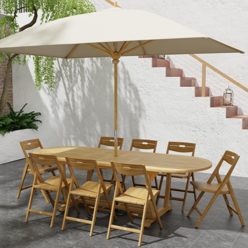70516 Montserrat Surf 9 pc Dining Set with optional umbrella in table center angled end view on stone patio with landscaping plants and stairs to house in background