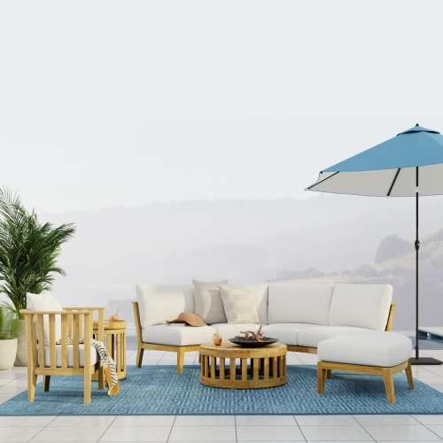 70940 Kafelonia 6 piece Sofa Sectional Set in side view on outdoor terrace one side lined with 2 potted plants next to optional opened blue umbrella with fog and hills in background