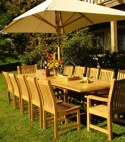 70017 Grand Veranda 13 piece Teak Dining Set with optional canvas rectangular umbrella on grass field