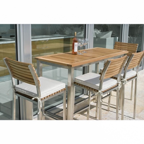 25314 Vogue 5 foot Rectangular Bar Set with optional seat cushions bottle of wine and 3 wine glasses on table set on concrete patio angled view with glass sliding doors in background