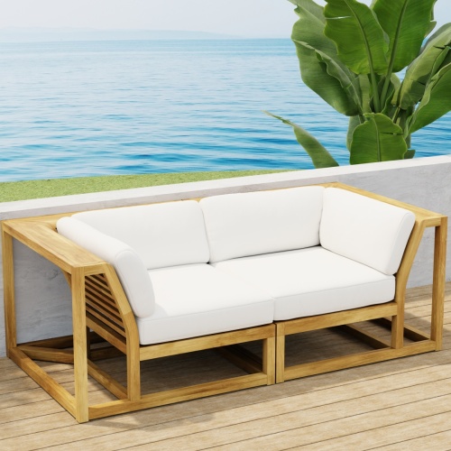 70275 Maya Love Seat of 2 Maya Corner Sectionals in angled end view on wood deck terrace with a plant and ocean and blue sky in the background