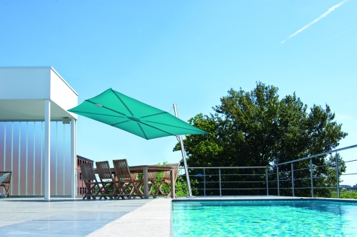 SP25100SET Spectra Solo Umbrella and Paver Base on pool deck over dining set next to covered area pool in front of set trees and blue sky in background