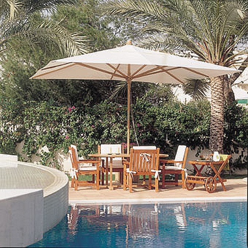 17640F Grand 10 feet Rectangular teak Umbrella opened in dining set with cushions and serving cart on outdoor deck with pool view and palm trees and shrubs in background