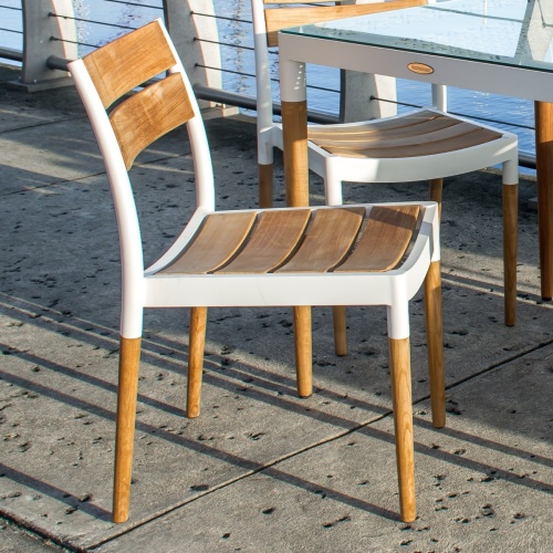 70542 Bloom teak and powder coated aluminum side chair angled side view on boat dock facing a marina in background