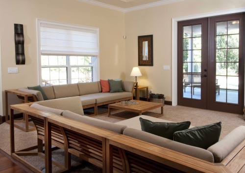 12800 maya teak corner frame with cushions collection set indoors on carpet facing french doors to outdoor patio with landscaped background