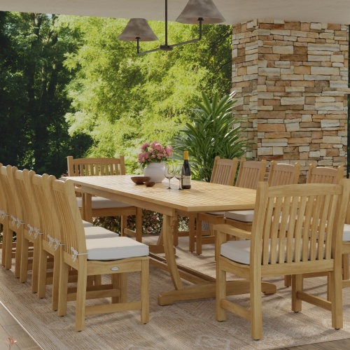70017 Grand Veranda 13 piece dining set with optional seat cushions in end view showing vase of flowers and wine glasses with bottle of wine on patio next to a stone wall 