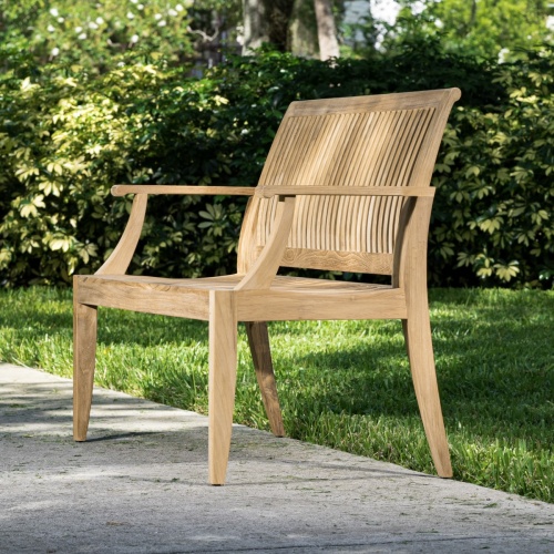 13810 Laguna 4 foot Teak Bench angled on concrete walkway with bushes in background