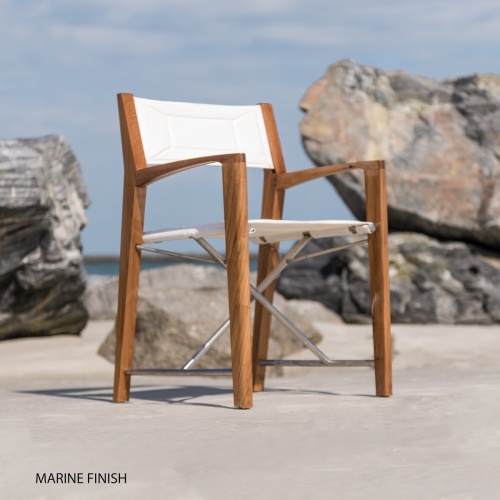 12915F Odyssey Folding Director Chair on sandy beach by boulder with ocean and blue sky in background